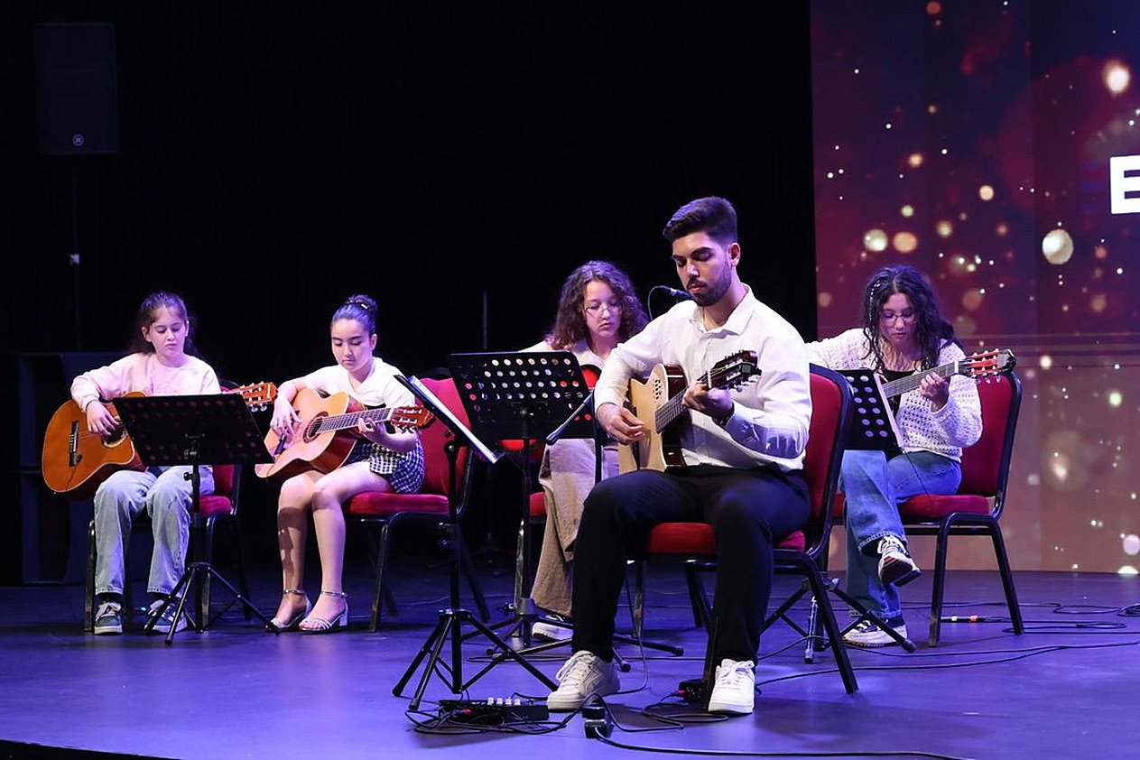 Eray Polat öğrencileriyle sahnede — çocuk gitar topluluğu konseri